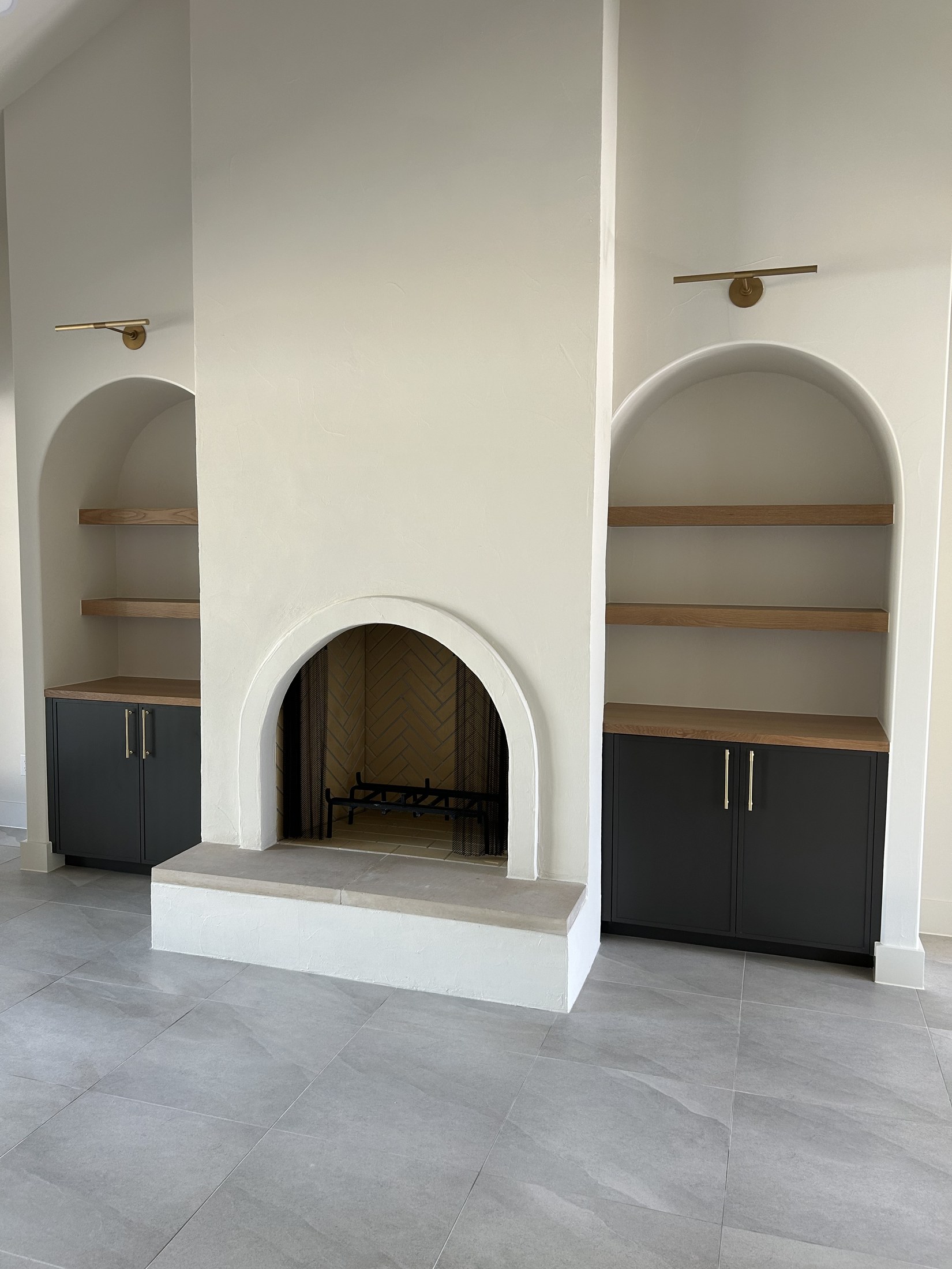 Arched plaster fireplace with built-in cabinetry and shelves