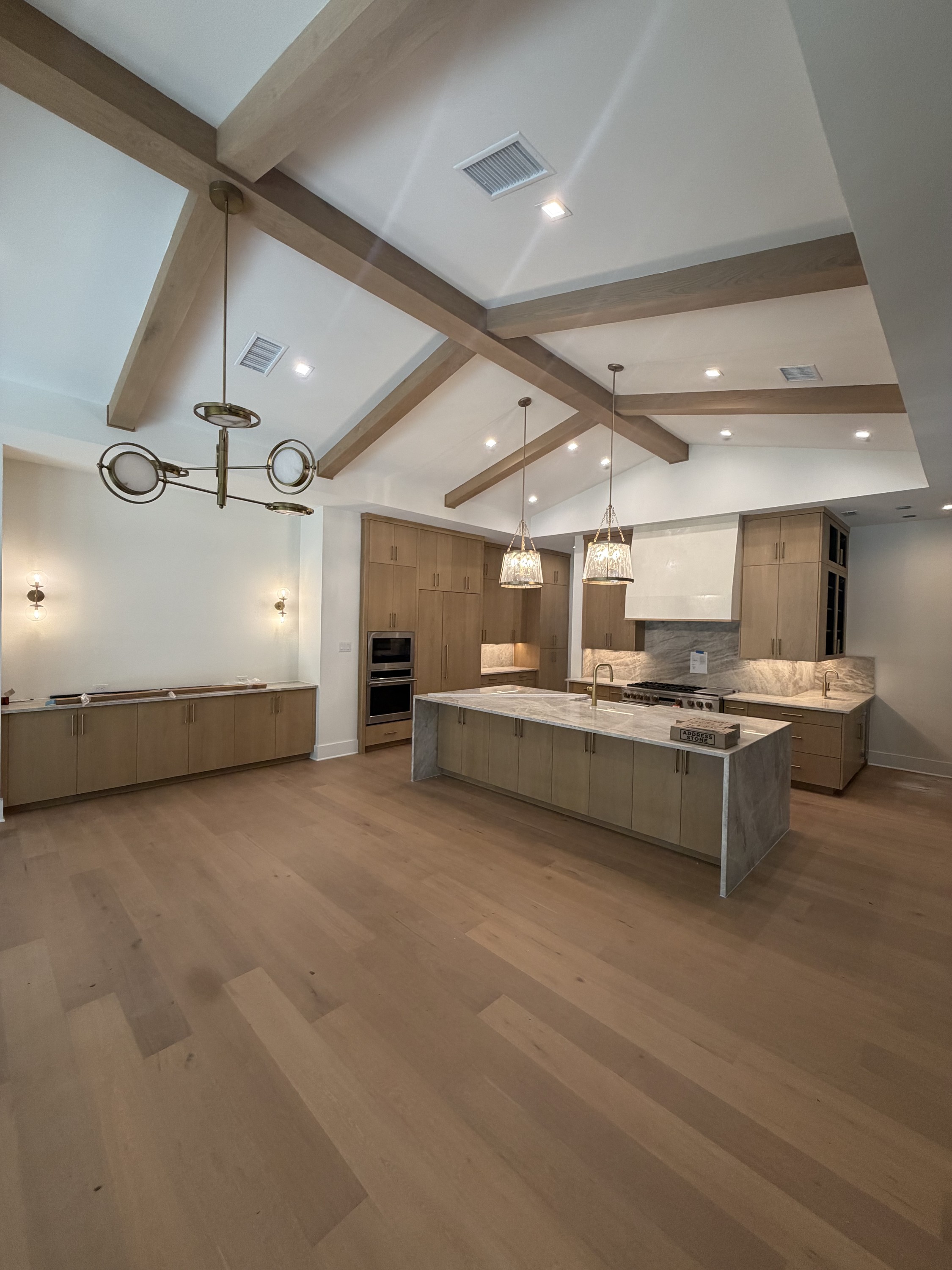 Vaulted great room with white oak cabinetry and a marble waterfall island